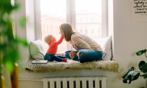 A mother and baby play on a window seat at home