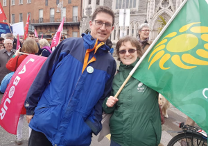 Green Party Leader Eamon Ryan and Green Party volunteer Mary Ryder wave a flag at a protest.
