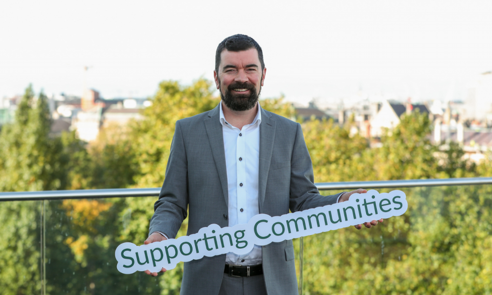 Joe O'Brien holds a sign reading 'Supporting Communities'