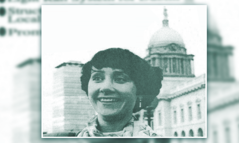 A black and white photo of a woman, Patricia McKenna, standing in front of the Custom House in Dublin.