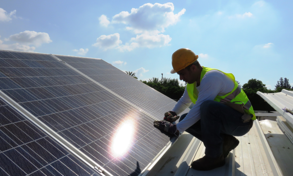 A man installs solar panels on a roof.