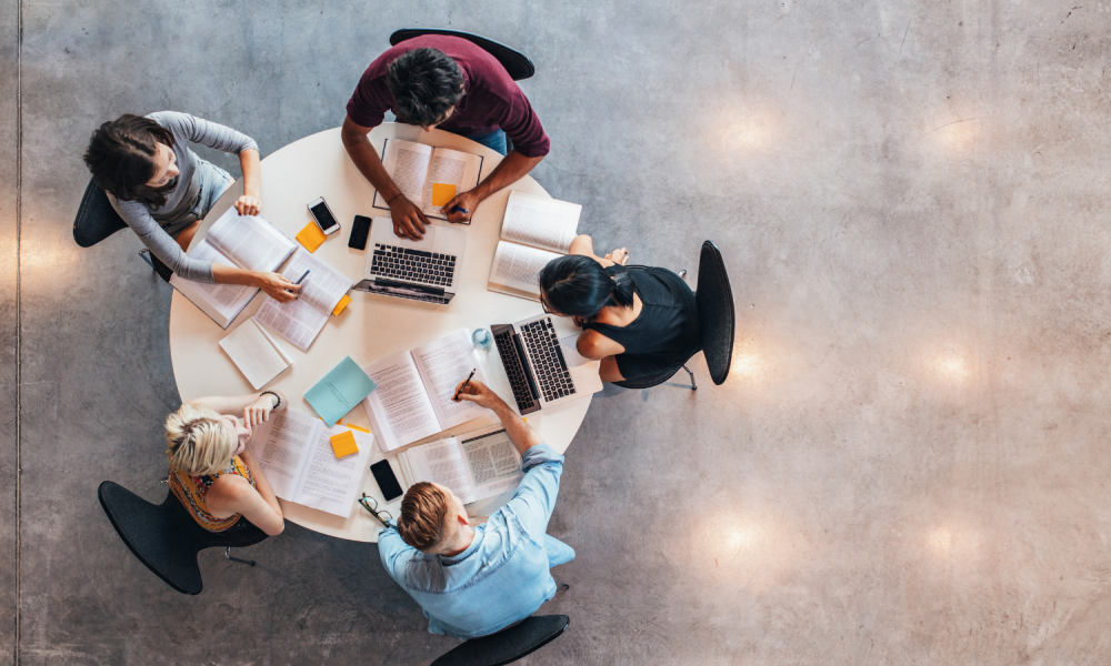 A group of people sit at a round table working on a project.